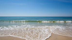 Ein Strand mit klarem, blauem Wasser und sanft anschwellenden Wellen.