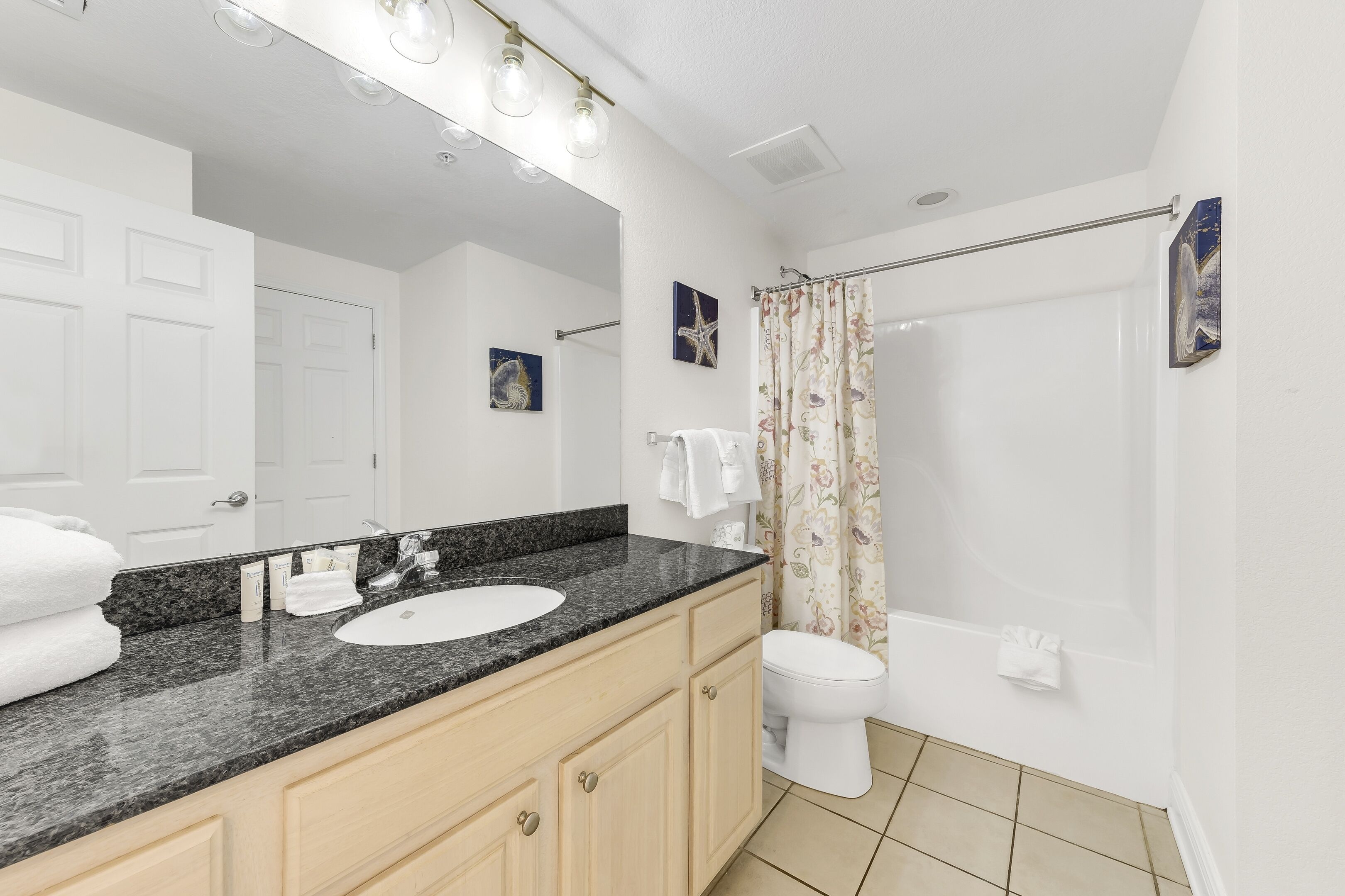 A bathroom with a white sink, a mirror, a toilet, and a shower curtain.