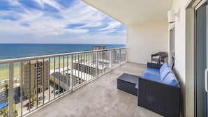 Ein Balkon mit Blick auf den Ozean, ein Rattansofa und ein Sessel.