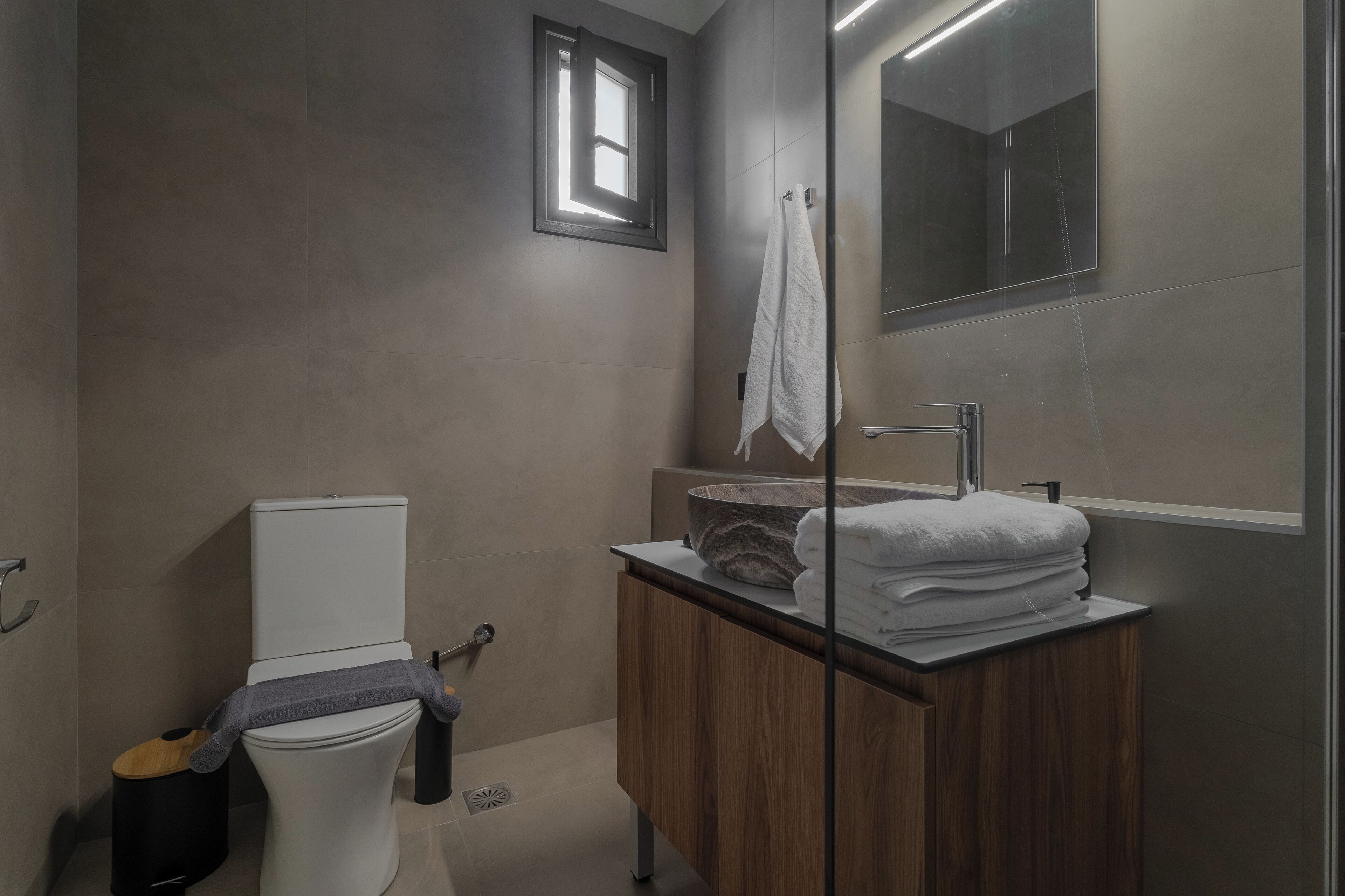 Een moderne badkamer met toilet, wastafel en spiegel.