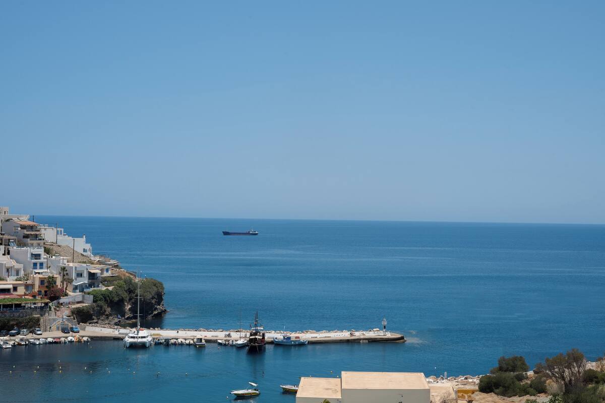A coastal town with a marina, boats, and buildings along the waterfront.