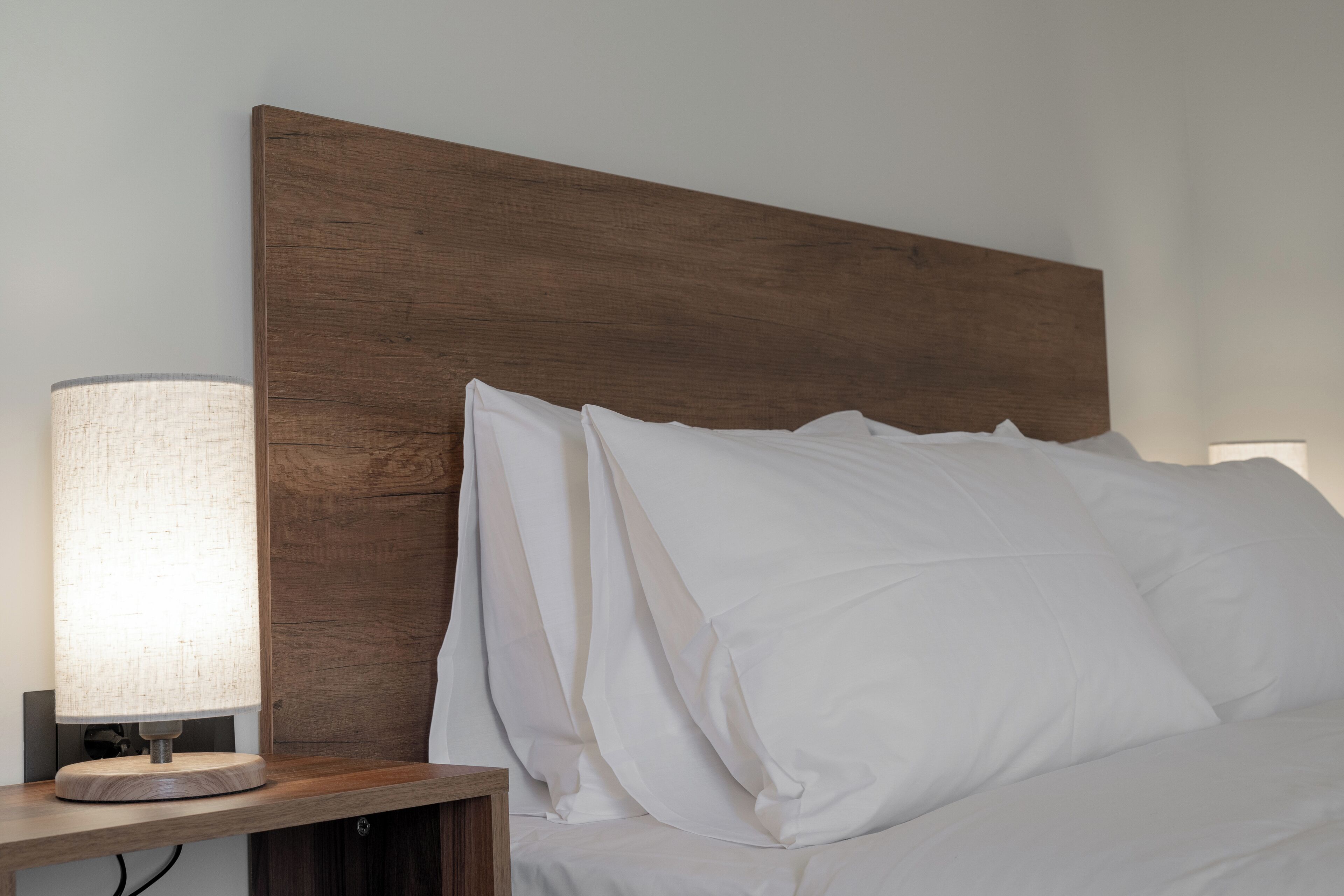 Una cama bien hecha con sábanas blancas y cabecera de madera.