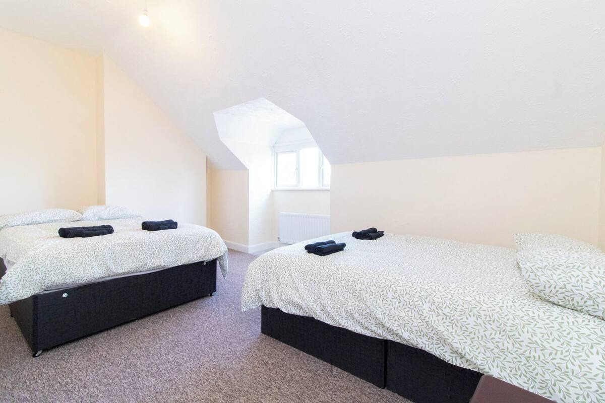 Ein Schlafzimmer mit zwei Betten, jeweils mit einem gemusterten Bettbezug und dunklen Kopfteilen.