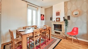 A dining area with a wooden table and chairs, a fireplace, and a red chair. - House for 8 in the center of Plouguerneau (Plouguerneau)