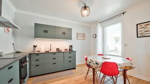 A modern kitchen with grey cabinets, a dining table with red chairs, and a pendant light. - House for 8 in the center of Plouguerneau (Plouguerneau)