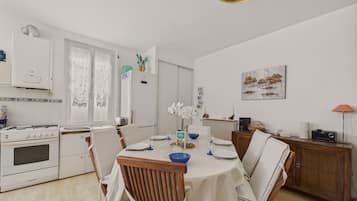 Un coin repas avec une table dressée pour quatre personnes, une cuisinière et un réfrigérateur dans la cuisine.