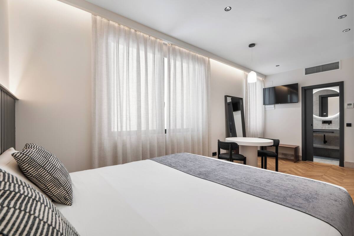Une chambre d’hôtel moderne avec un grand lit, une petite table et un téléviseur.