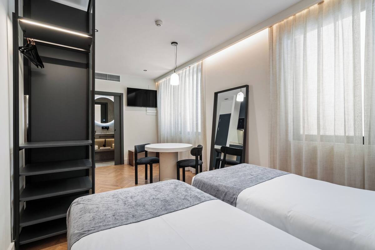 Une chambre d’hôtel moderne équipée de deux lits, d’un bureau et d’une armoire.