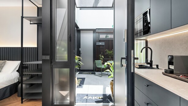 Habitación de hotel moderna con cama, escritorio y kitchenette.
