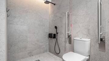 Un baño moderno con ducha, inodoro y barras de apoyo.