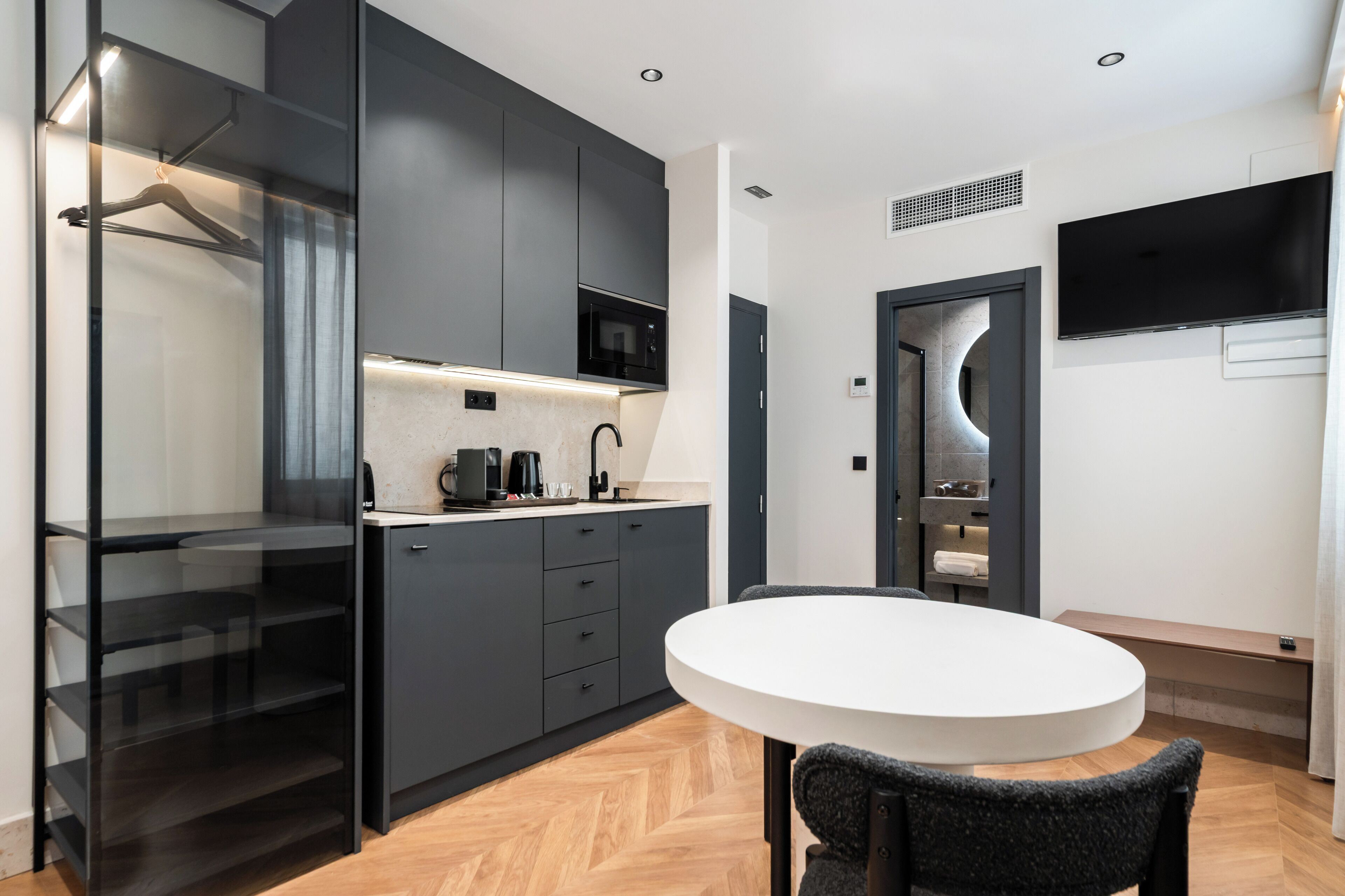 Una cocina moderna con armarios grises, una encimera blanca y una mesa redonda blanca con una silla.