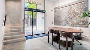 Un moderno vestíbulo de hotel con una pared de mármol, un ventanal grande, una mesa de conferencias y una escalera.