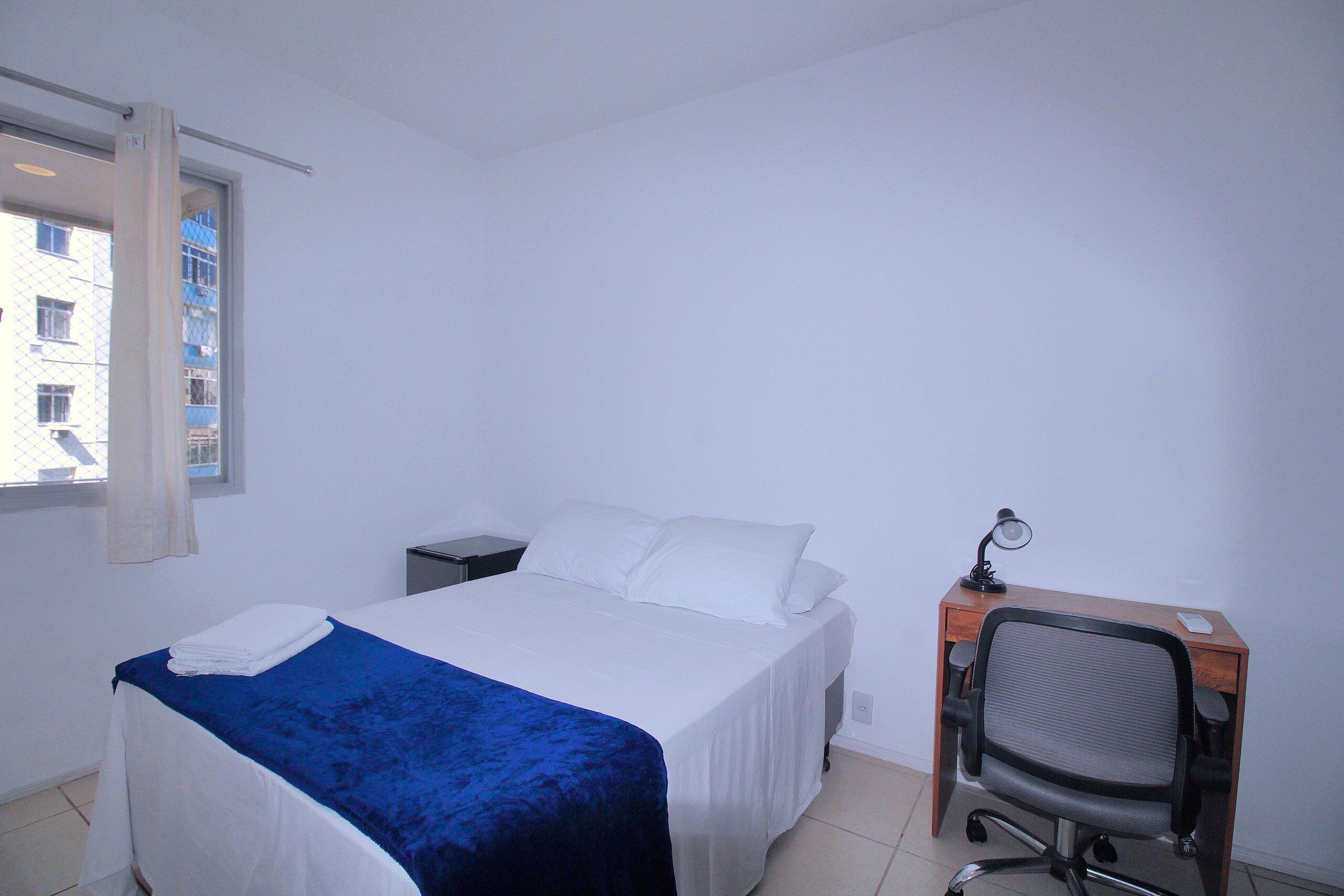 A bedroom with a bed, a desk, and a chair.