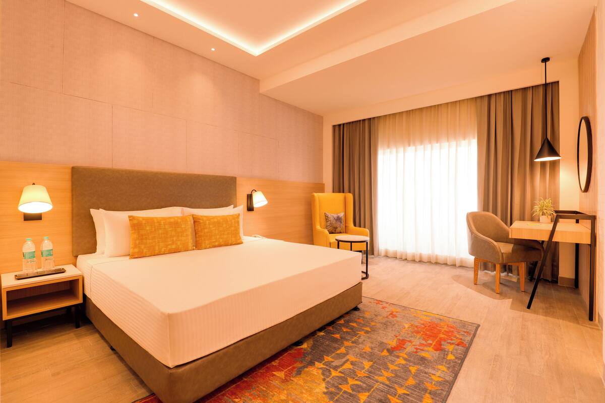 A hotel room with a large bed, bedside tables, a desk, and a chair.