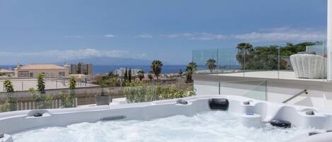 A rooftop jacuzzi with a clear view of the ocean and cityscape.