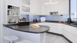 Eine moderne Küche mit weißen Schränken, einer gebogenen Kochinsel mit Barhocker und einem eingebauten Backofen.