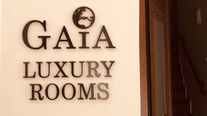 Een wandbordje voor 'GAIA LUXURY ROOMS' met een logo van een wereldbol.