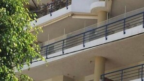 Un immeuble à plusieurs étages, doté de balcons et de colonnes, avec un ciel dégagé.