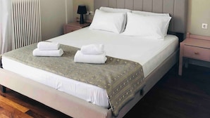 Un lit double bien fait, avec une couvre-lit à motifs et deux oreillers, une table de chevet avec une lampe et un climatiseur fixé au mur.