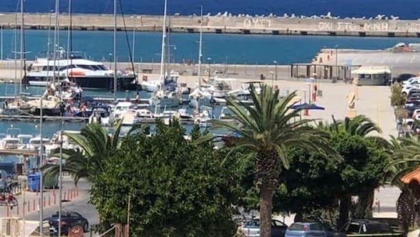 Un port de plaisance avec des bateaux amarrés, une plage de sable et un ciel bleu dégagé.