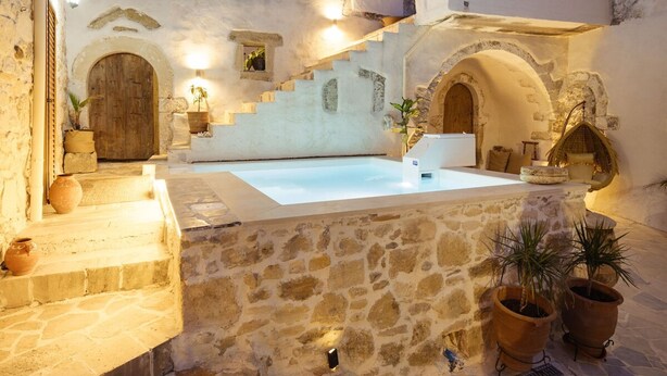 Um pátio com piscina, degraus de pedra e portas em arco.