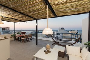 Una terraza en la azotea con zona de comedor, una hamaca y vistas al mar.