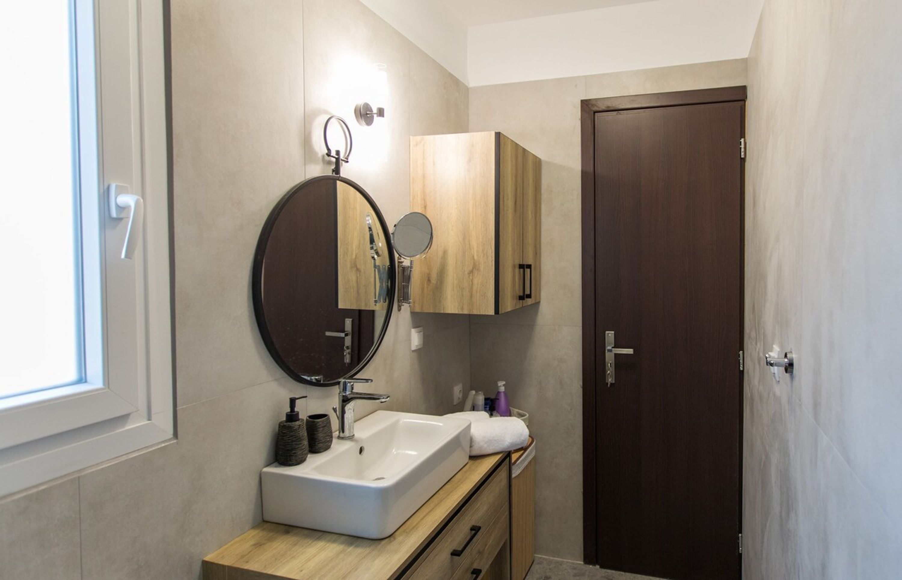 A modern bathroom with a large mirror, a sink, and wooden cabinets.