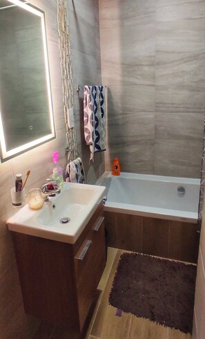 Ein Badezimmer mit großem Spiegel, Waschbecken, Badewanne und Duschvorhang.