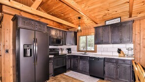 Une cuisine moderne avec des meubles de couleur bois foncé, des appareils en acier inoxydable et un plafond en bois.