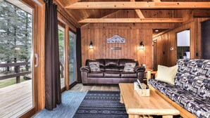 L'intérieur d'une cabane, avec un canapé en cuir, un canapé à motifs, une table en bois et une pancarte indiquant « Bienvenue dans la cabane ».
