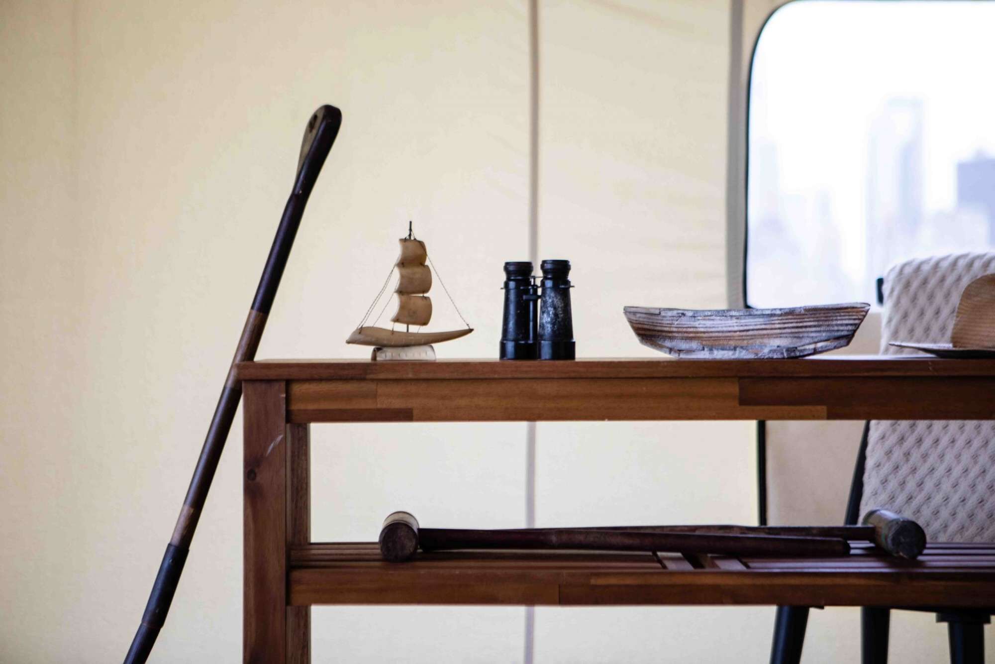A wooden table with a small ship model, binoculars, and a bowl.
