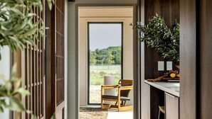 A modern kitchen with a view of a balcony, a wooden chair, and a plant on the counter. - Luxurious Glamping | Panoramic Views & Dining (New York)