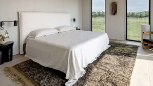 A modern bedroom with a large bed, a view of the outdoors, and a minimalist design. - Luxurious Glamping | Panoramic Views & Dining (New York)
