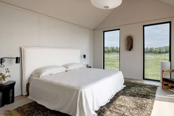 Bright bedroom with king bed, two tall windows, and soft rug