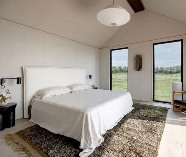 Ein modernes Schlafzimmer mit einem großen Bett, Blick ins Freie und minimalistischem Design.