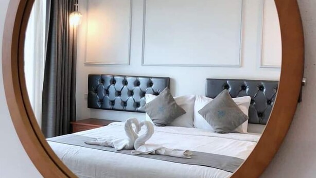 Ein Schlafzimmer mit einem großen, runden Spiegel, einem gepolsterten Kopfteil und einem Bett mit Kissen.