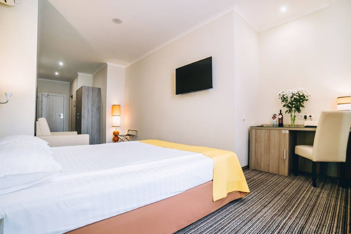 Une chambre d’hôtel équipée d’un lit, d’un bureau, d’une chaise, d’une télévision et d’un miroir.