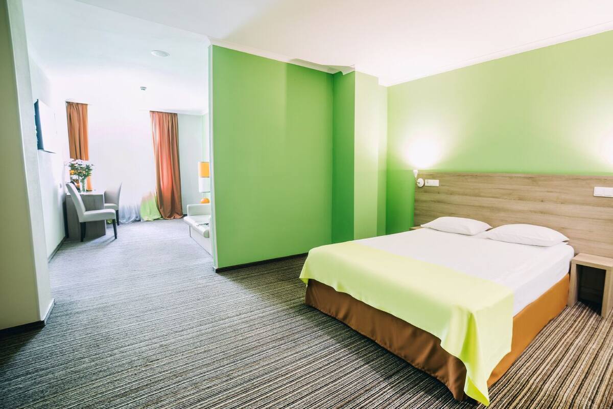 Une chambre d’hôtel avec un lit, une table de chevet, un bureau et une chaise.