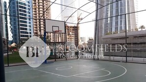 Ein Basketballplatz mit Korb, umgeben von Hochhäusern und Neubauten.