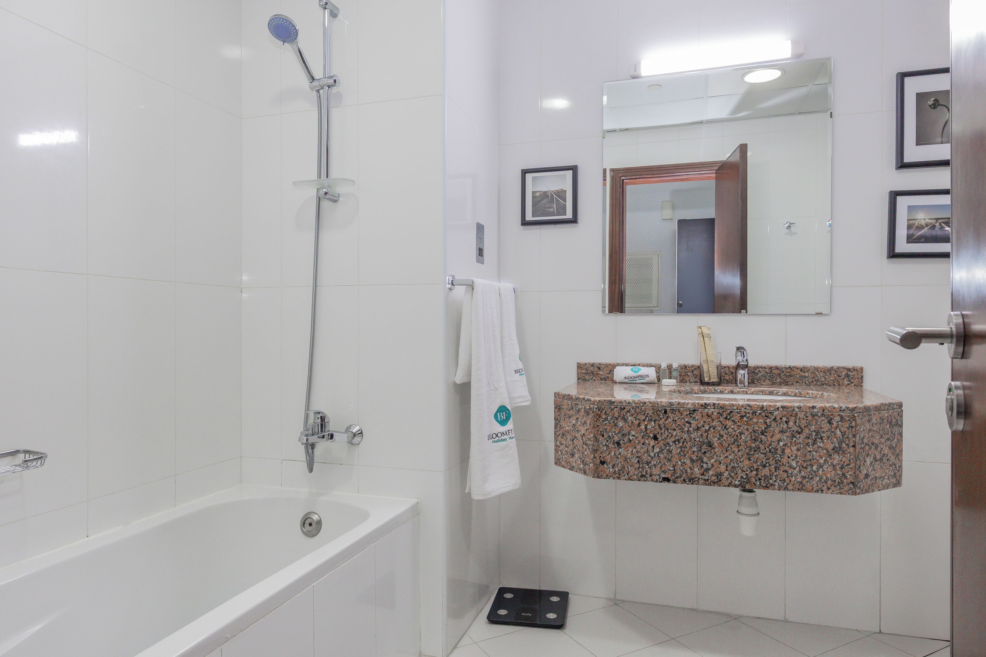 A bathroom with a bathtub, a shower, a sink with a granite countertop, and a mirror above the sink.