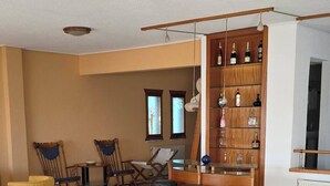A spacious living area with a sofa, chairs, a coffee table, and a wooden bar with shelves. - Breathtaking Seaview Villa with Pool near Athens (Theologos)