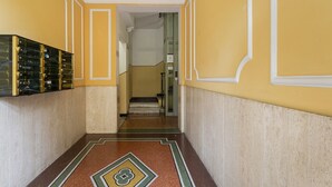 Un pasillo con paredes amarillas, piso estampado y una escalera que lleva a otra habitación.