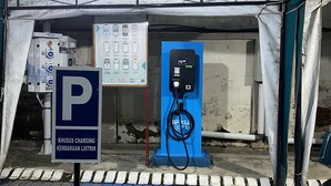 Ein Zelt mit einer blauen Ladesäule für Elektrofahrzeuge und einem Schild, das einen Parkplatz kennzeichnet.
