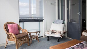 A balcony with wicker furniture, a glass table, and a sofa with a cowhide blanket. - Kotimaailma Deluxe Apartment Lake View (Lahti)