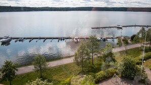 A marina with boats docked, a walking path, and a view of a calm lake. - Kotimaailma Deluxe Apartment Lake View (Lahti)