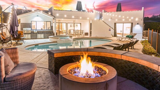 Un jardin avec une piscine, un espace salon extérieur et un foyer.