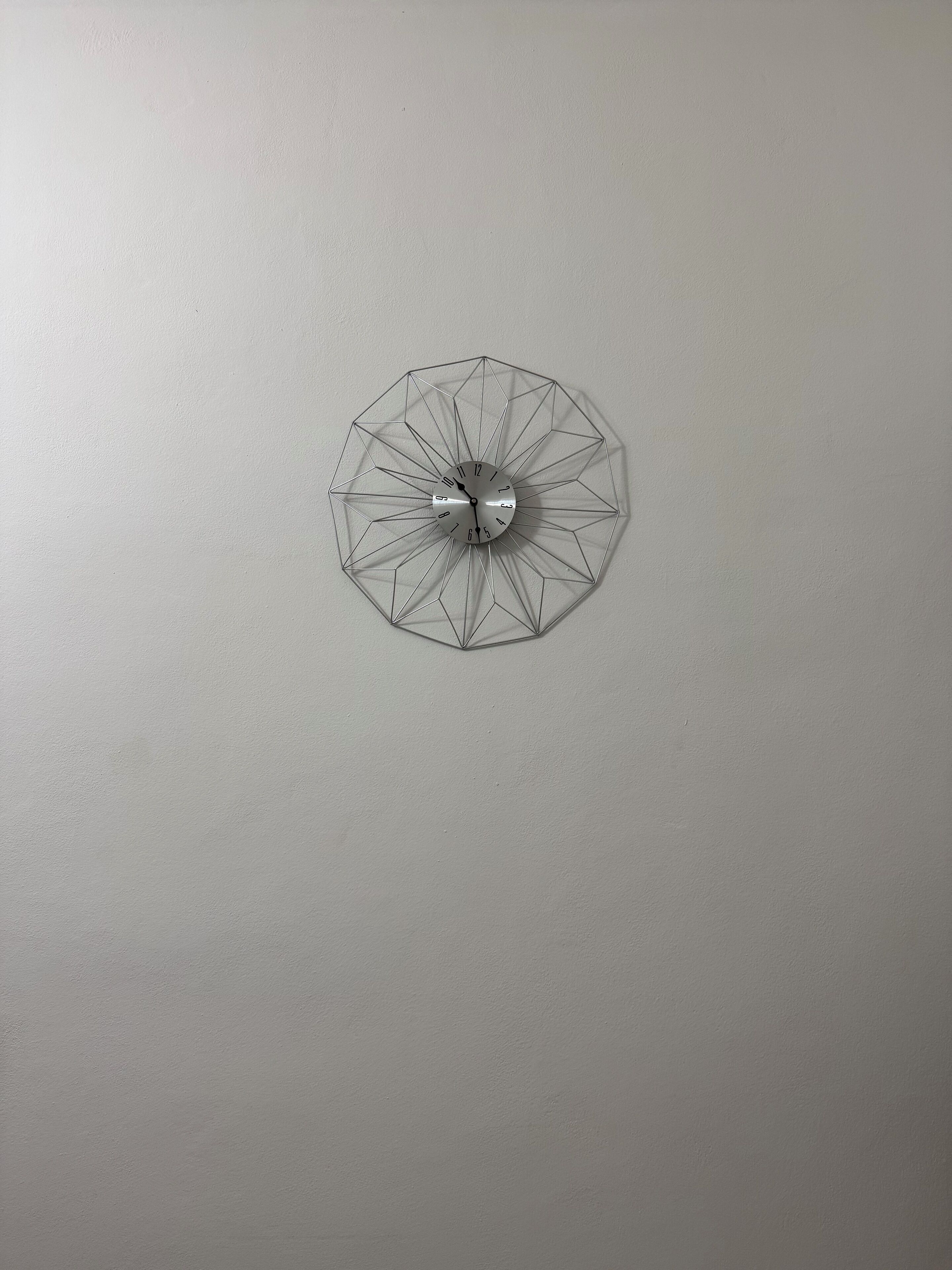 Une horloge murale au design géométrique, avec une finition métallique.