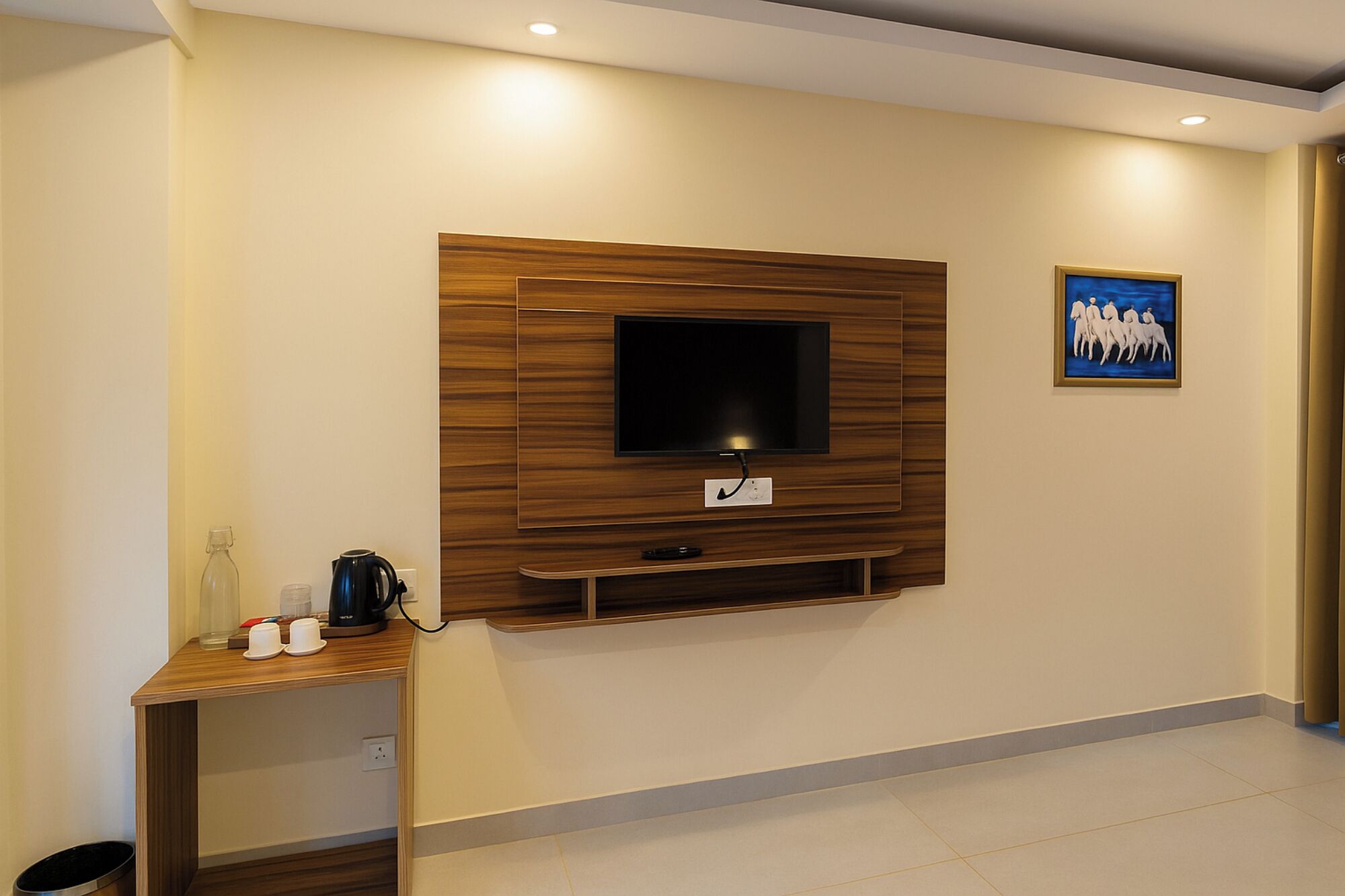 A modern living room with a mounted TV, a coffee maker, and a small table with cups.