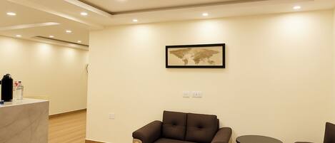 A hotel room with a sofa, a small round table, and a world map on the wall.