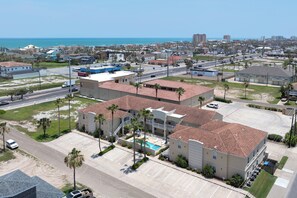 Un hotel de varios pisos con piscina, estacionamiento y vista al océano.